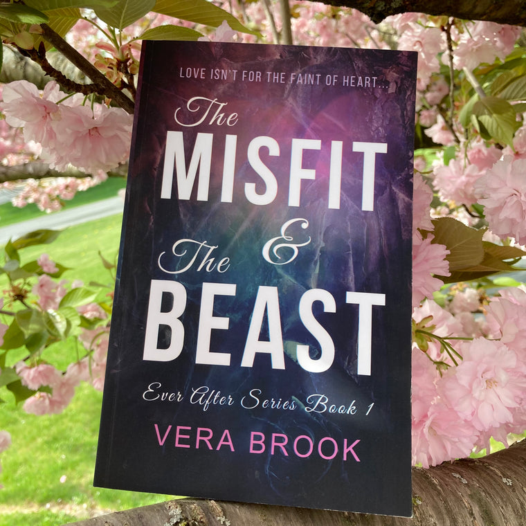 Paperback of The Misfit and The Beast by Vera Brook on a blooming cherry tree.